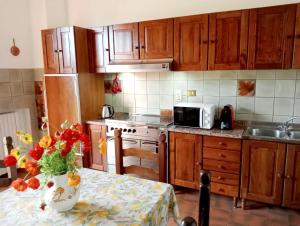 uma cozinha com armários de madeira e uma mesa com um vaso de flores em Poggio Leporaia em Lamporecchio