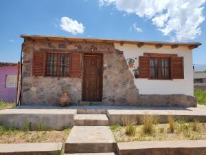 a small stone house with wooden shuttered windows at El Cobijo del Artista - en Huacalera in Huacalera