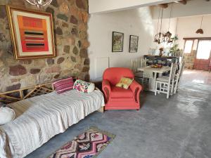 a living room with a red chair and a stone wall at El Cobijo del Artista - en Huacalera in Huacalera