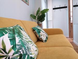 a couch with two pillows on it in a living room at Suite Monstera by Welk'Home Inn - Appartement Premium - Troyes Centre in Troyes