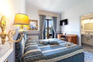 una camera da letto con un letto con una lampada e uno specchio di Hotel Sant'Agata a SantʼAgata sui Due Golfi