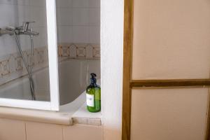 a green bottle of soap sitting on a shelf next to a bath tub at MONOLOCALE CASENUOVE con GIARDINO in Castiglioncello