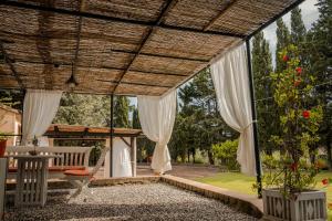 a screened in porch with white curtains and a bench at MONOLOCALE CASENUOVE con GIARDINO in Castiglioncello