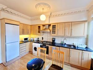 een keuken met witte apparaten en houten kasten bij Beautiful Kensington Home by Earl's Court Station in Londen
