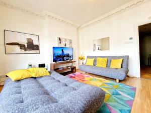 een woonkamer met een bank en een tv bij Beautiful Kensington Home by Earl's Court Station in Londen
