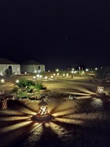 two lights in the middle of a field at night at Sahara Desert Trips & Camps in Merzouga