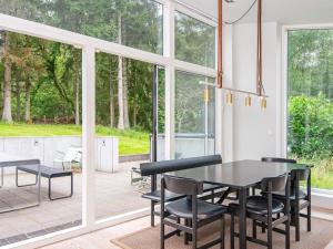 a dining room with a table and chairs and windows at 8 person holiday home in Ebeltoft in Ebeltoft