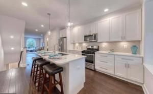 a kitchen with white cabinets and a kitchen island with bar stools at Beautiful Canton Home w/rooftop deck +Private parking in Baltimore