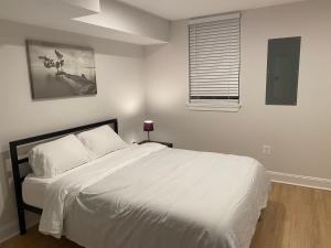 um quarto com uma cama branca e uma janela em Beautiful Canton Home w/rooftop deck +Private parking em Baltimore