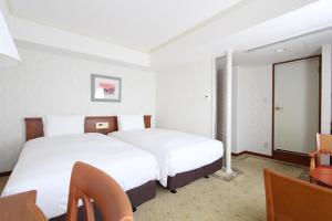 名古屋市にあるKOKO Hotel 名古屋栄のベッド2台とテーブルが備わるホテルルームです。