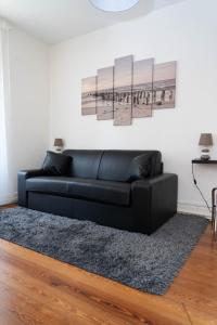 Beau T2 quartier Contades في ستراسبورغ: أريكة سوداء في غرفة معيشة مع سجادة