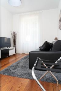 sala de estar con sofá negro y TV en Beau T2 quartier Contades en Estrasburgo