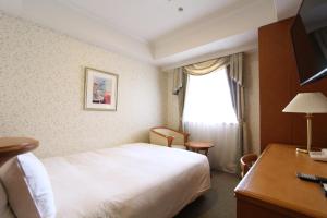 Cette chambre comprend un lit, un bureau et une fenêtre. dans l'établissement KOKO HOTEL Osaka Shinsaibashi, à Osaka