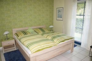 - une chambre dotée d'un grand lit avec des draps verts et jaunes dans l'établissement Ostseewelle, à Schönberger Strand