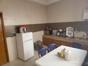 a kitchen with a white refrigerator and a table and chairs at Appartement near airport ouled tayeb in Al Hachlaf