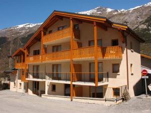 un gran edificio de apartamentos con balcones y montañas cubiertas de nieve en Appartement Lanslevillard, 3 pièces, 6 personnes - FR-1-508-12, en Lanslevillard