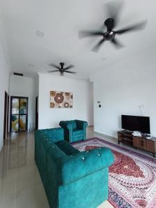 ein Wohnzimmer mit einem grünen Sofa und zwei Deckenventilatoren in der Unterkunft Homestay Besut in Kampung Raja