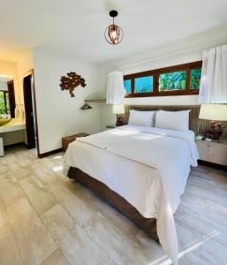 a bedroom with a large white bed and windows at The Madalena Pousada in Imbassai