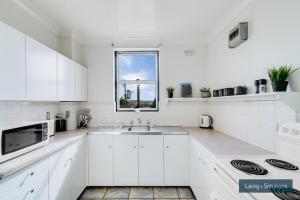 uma cozinha branca com um lavatório e uma janela em TC GARDENS 12 em Armidale