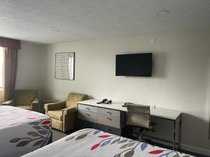 a hotel room with a desk and a tv on the wall at Ramada by Wyndham Indianapolis Speedway in Indianapolis