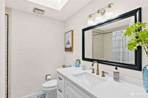 ein weißes Badezimmer mit einem Waschbecken und einem Spiegel in der Unterkunft Secluded Sanctuary With a View of The Puget Sound in Gig Harbor