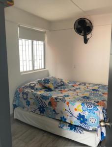 1 dormitorio con 1 cama con colcha de flores y ventana en Aparta Sol San Jeronimo, en San Jerónimo