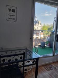 Zimmer mit einem Tisch und Blick auf einen Balkon in der Unterkunft DANA S HOME in La Courneuve