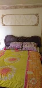 ein Bett mit einer gelben Decke und Kissen darauf in der Unterkunft الفيصل in Port Said