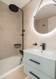 een badkamer met een wastafel, een spiegel en een bad bij Elurra II Confort in Formigal