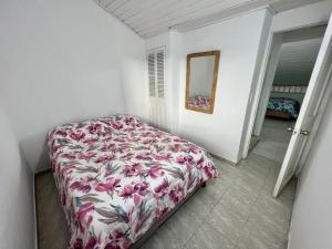 1 dormitorio con 1 cama con colcha de flores en Maja Hospedaje Apartamento con aire frente al Mar, en Cartagena de Indias