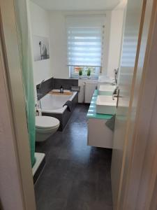 La salle de bains est pourvue de 2 lavabos, de toilettes et d'une baignoire. dans l'établissement Ferienwohnung am Bodensee, à Öhningen
