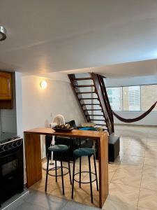 una cocina con una mesa con taburetes y una escalera en Maja Hospedaje Apartamento con aire frente al Mar en Cartagena de Indias