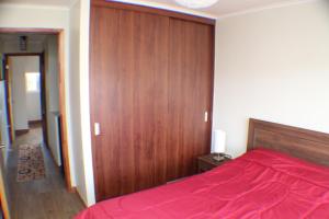 a bedroom with a red bed and a wooden wall at Depto a orilla del río Calle Calle in Valdivia