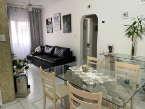 Charmoso apartamento 01 Quarto Enseada في غوارويا: غرفة معيشة مع طاولة زجاجية وأريكة