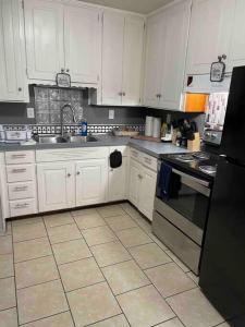 a kitchen with white cabinets and a black refrigerator at Cozy 4 Bedroom Near Airport in Montgomery