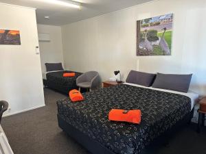 Habitación de hotel con cama y silla en Winton Outback Motel en Winton
