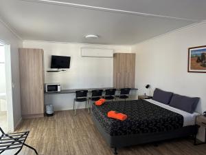 1 dormitorio con 1 cama, sillas y TV en Winton Outback Motel en Winton