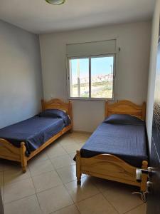 2 camas en una habitación con ventana en appartement in al hoceima, en Alhucemas