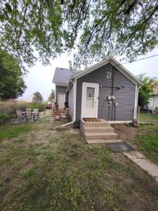 a small gray house with a white door and stairs at Cozy Little Getaway in Winner