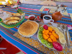 a table with a breakfast of pancakes and fruit at Lake View Lodge in Puno