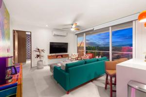 a living room with a green couch and a large window at 3 bedroom luxury condo next to beach & pools, ac and internet in Akumal