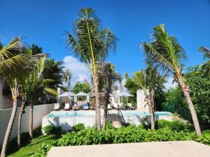 a villa with palm trees and a swimming pool at 3 bedroom luxury condo next to beach & pools, ac and internet in Akumal