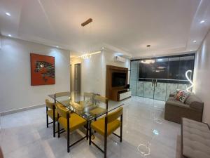 a dining room with a glass table and yellow chairs at Refúgio Costeiro in Guarujá