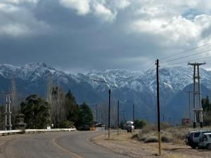 a street with cars parked on a road with snow covered mountains at RAMA GUEST HOUSE in Ciudad Lujan de Cuyo