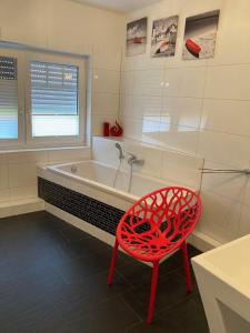 einem roten Stuhl vor einer Badewanne in der Unterkunft Villa Sienna in Zingst