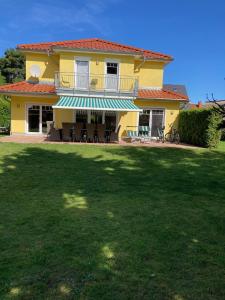 ein gelbes Haus mit Rasen davor in der Unterkunft Villa Sienna in Zingst