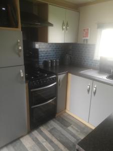 uma cozinha com armários brancos e um fogão preto em The Powers em Rhyl