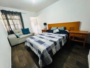 1 dormitorio con cama, mesa y sofá en Cómoda casa con dos cuartos y cochera para auto pequeño, en Guadalajara