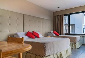 um quarto de hotel com duas camas com almofadas vermelhas em Miralejos em Ushuaia