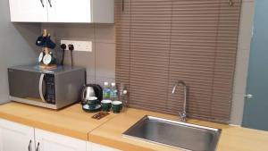 eine Küchentheke mit einer Spüle und einer Mikrowelle in der Unterkunft Champs Elysees in Kampar